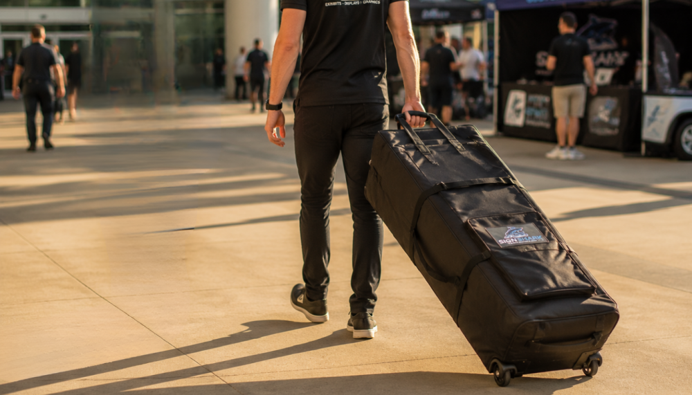 Two event team members easily wheeling a heavy-duty canopy tent roller bag